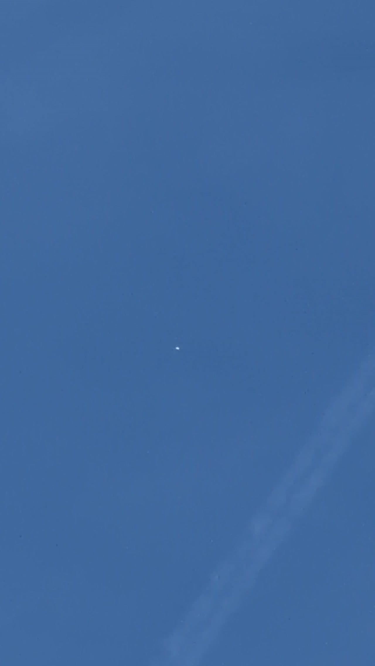 Small reflective object filmed above North London as an aircraft passes